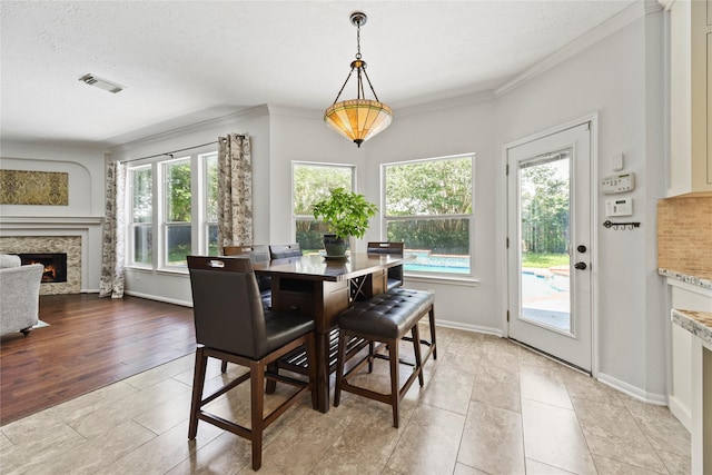 4019 Bellinger Way, Missouri City, TX 77459 - dining area featuring a stone fireplace, light tile patterned floors, ornamental molding, baseboards, and a textured ceiling