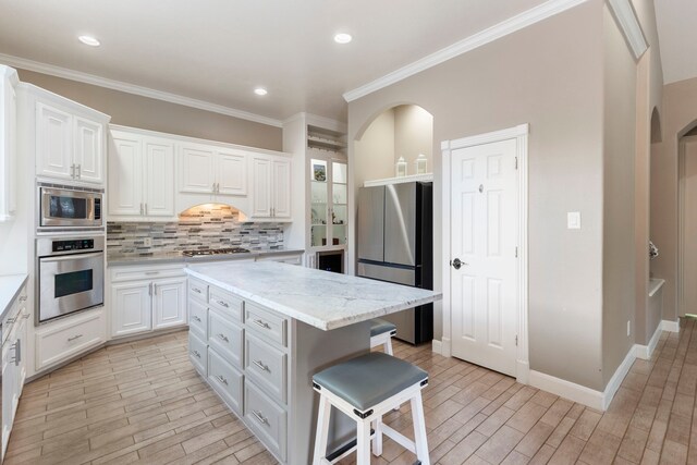 13207 Regency Oak Ln, Cypress, TX 77429 - kitchen with appliances with stainless steel finishes, backsplash, light wood finished floors, white cabinetry, and crown molding