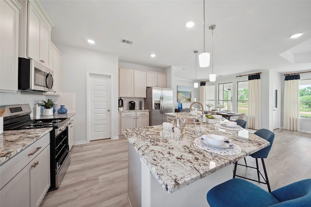 701 Barton Place Dr, Cleveland, TX 77327 - kitchen featuring appliances with stainless steel finishes, a sink, light wood-type flooring, a breakfast bar area, and backsplash