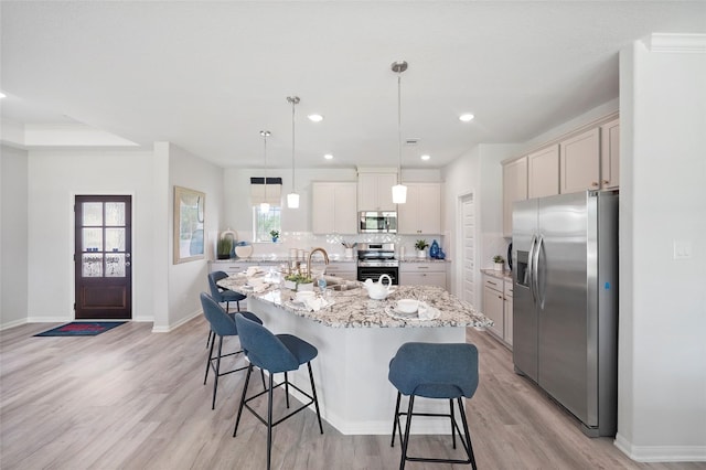 701 Barton Place Dr, Cleveland, TX 77327 - kitchen with stainless steel appliances, a breakfast bar area, light wood finished floors, a sink, and a center island with sink