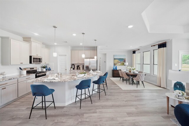701 Barton Place Dr, Cleveland, TX 77327 - kitchen featuring stainless steel appliances, a kitchen breakfast bar, light wood-type flooring, a spacious island, and light stone countertops