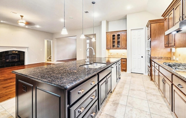 18618 Arlan Lake Dr, Spring, TX 77388 - kitchen featuring a sink, stainless steel appliances, a kitchen island with sink, a tiled fireplace, and dark stone countertops
