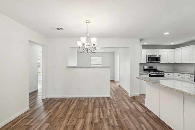 6038 Woodbrook Ln, Houston, TX 77008 - kitchen featuring stainless steel appliances, a chandelier, light wood finished floors, white cabinets, and recessed lighting
