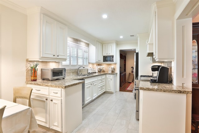 6235 Queenswood Ln, Houston, TX 77008 - kitchen with stainless steel microwave, crown molding, a sink, white cabinets, and recessed lighting
