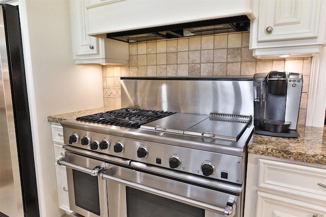 6235 Queenswood Ln, Houston, TX 77008 - kitchen with stainless steel appliances, under cabinet range hood, backsplash, white cabinetry, and stone counters