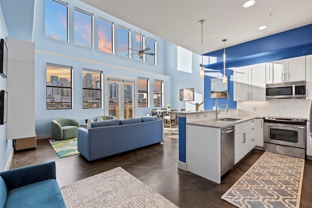 2323 Polk St Unit 302, Houston, TX 77003 - kitchen featuring appliances with stainless steel finishes, open floor plan, a peninsula, white cabinets, and light stone counters