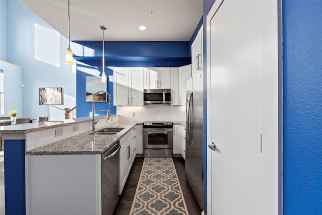 2323 Polk St Unit 302, Houston, TX 77003 - kitchen featuring appliances with stainless steel finishes, a sink, a peninsula, white cabinets, and light stone countertops