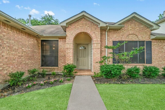 31115 Perlican Dr, Spring, TX 77386 - doorway to property featuring brick siding, a lawn, and a shingled roof