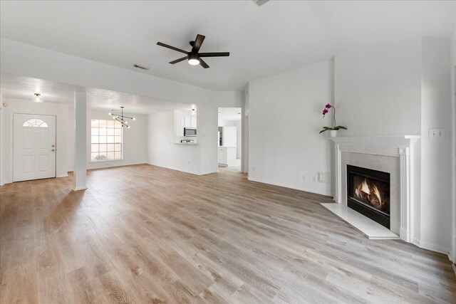 31115 Perlican Dr, Spring, TX 77386 - unfurnished living room with a glass covered fireplace, ceiling fan, light wood-style floors, and a chandelier
