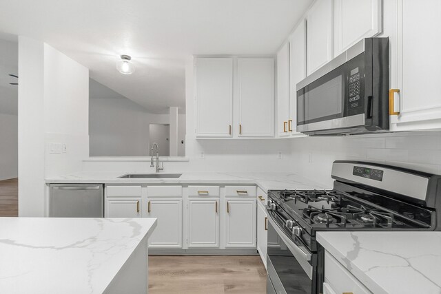 31115 Perlican Dr, Spring, TX 77386 - kitchen featuring stainless steel appliances, a sink, light wood finished floors, and white cabinetry