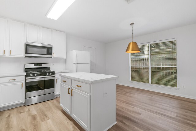 31115 Perlican Dr, Spring, TX 77386 - kitchen featuring appliances with stainless steel finishes, light wood-type flooring, white cabinets, hanging light fixtures, and a center island