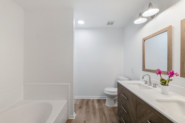 31115 Perlican Dr, Spring, TX 77386 - bathroom featuring a bath, wood finished floors, toilet, double vanity, and baseboards