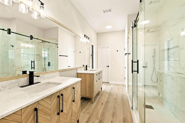 50 E Copper Sage Cir, The Woodlands, TX 77381 - bathroom with a marble finish shower, two vanities, and wood finished floors