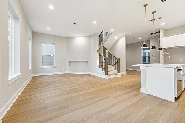 807 Martin St Unit D, Houston, TX 77018 - kitchen with light wood-type flooring, a center island with sink, white cabinets, pendant lighting, and light countertops