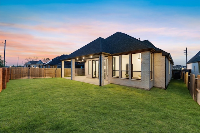 9114 Pleasant Grove Ct, Missouri City, TX 77459 - back of property at dusk featuring roof with shingles, brick siding, and a patio