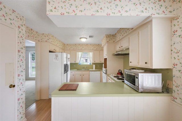 10722 Glenway Dr, Houston, TX 77070 - kitchen with wallpapered walls, white appliances, a sink, light wood finished floors, and under cabinet range hood
