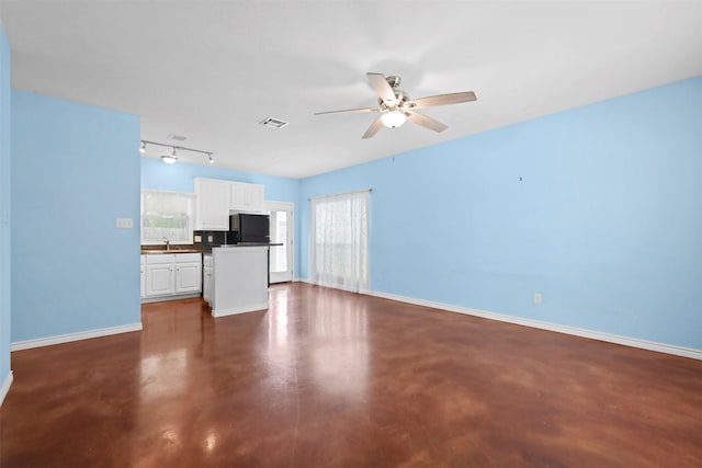615 Columbus St, College Station, TX 77840 - unfurnished living room featuring concrete floors, ceiling fan, baseboards, track lighting, and a sink