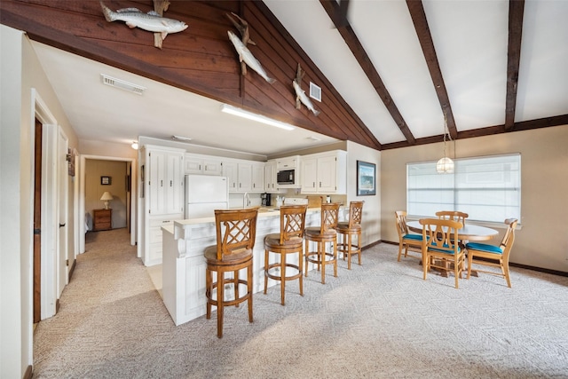 215 Selkirk Rd, Matagorda, TX 77414 - kitchen with freestanding refrigerator, light colored carpet, black microwave, baseboards, and white cabinets