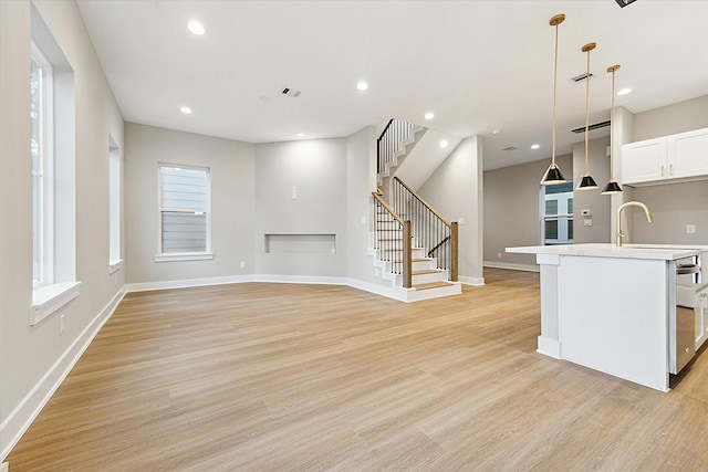807 Martin St Unit C, Houston, TX 77018 - kitchen with light wood-type flooring, a center island with sink, white cabinets, pendant lighting, and light countertops
