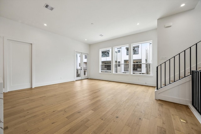 2209 Dennis St, Houston, TX 77004 - unfurnished living room featuring light wood-type flooring, stairway, recessed lighting, baseboards, and french doors