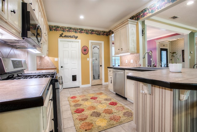 1912 Rollingwood Dr, Huntsville, TX 77340 - kitchen with appliances with stainless steel finishes, tile counters, a sink, cream cabinets, and light tile patterned floors
