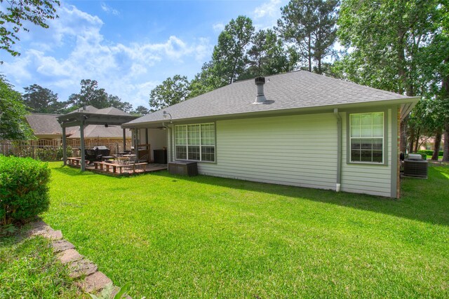 1912 Rollingwood Dr, Huntsville, TX 77340 - back of property featuring a ceiling fan, roof with shingles, cooling unit, and a patio