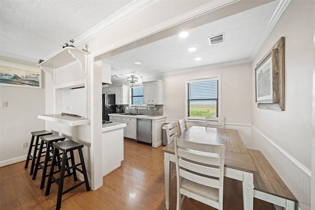 109 Fm-2031, Matagorda, TX 77457 - kitchen with stainless steel dishwasher, crown molding, a kitchen breakfast bar, freestanding refrigerator, and a peninsula