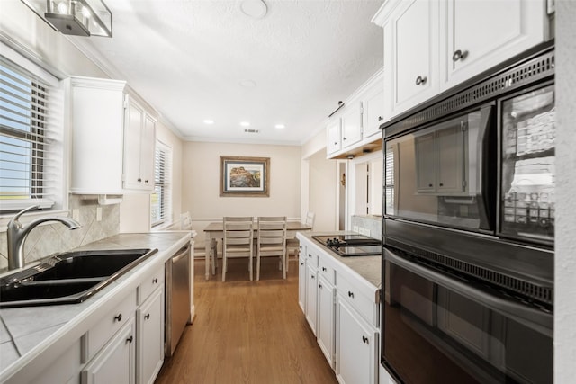 109 Fm-2031, Matagorda, TX 77457 - kitchen featuring a sink, black appliances, white cabinets, ornamental molding, and tile countertops