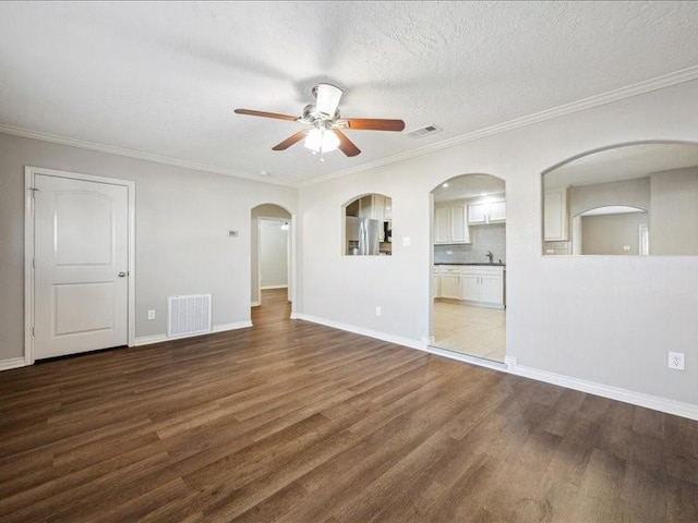 7205 Yucca Dr, Galveston, TX 77551 - empty room with ceiling fan, wood finished floors, arched walkways, baseboards, and crown molding