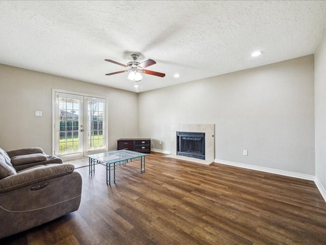 7205 Yucca Dr, Galveston, TX 77551 - living area featuring wood finished floors, a ceiling fan, a textured ceiling, baseboards, and a fireplace with flush hearth