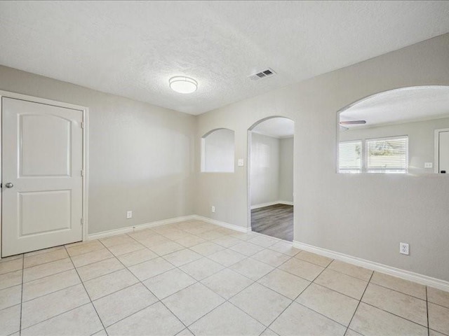 7205 Yucca Dr, Galveston, TX 77551 - empty room featuring arched walkways, tile patterned flooring, a textured ceiling, and baseboards