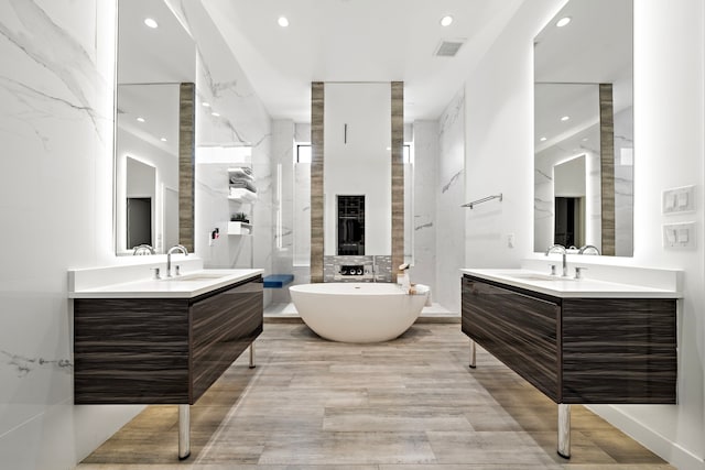 819 W 24th St Unit C, Houston, TX 77008 - bathroom featuring recessed lighting, two vanities, a soaking tub, a fireplace, and wood finished floors