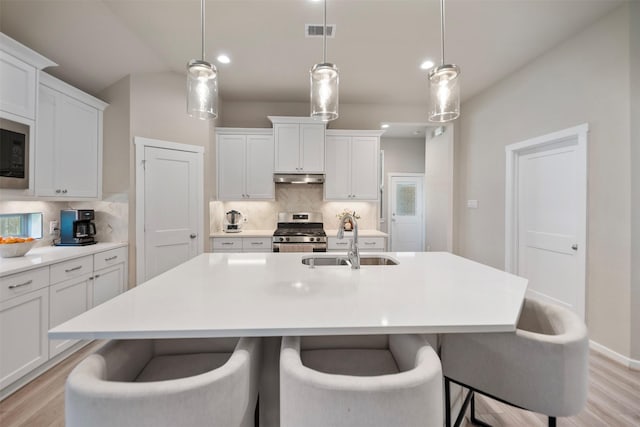 4607 Primrose Valley Ln, Fulshear, TX 77441 - kitchen with a sink, gas range, under cabinet range hood, tasteful backsplash, and recessed lighting