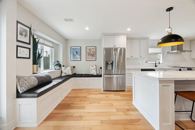 10310 Helmsdale St, Houston, TX 77043 - kitchen with stainless steel fridge, light wood-style flooring, decorative backsplash, a kitchen breakfast bar, and pendant lighting