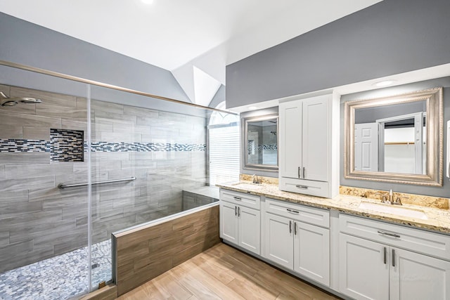 6614 Cypress Village Dr, Sugar Land, TX 77479 - bathroom featuring a stall shower, vaulted ceiling, double vanity, and wood finished floors