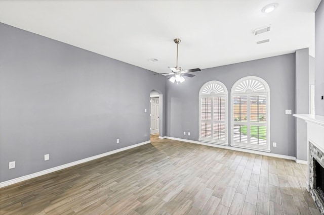 6614 Cypress Village Dr, Sugar Land, TX 77479 - unfurnished living room featuring light wood-style flooring, a fireplace, ceiling fan, arched walkways, and baseboards
