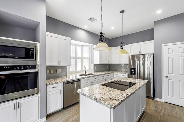6614 Cypress Village Dr, Sugar Land, TX 77479 - kitchen featuring appliances with stainless steel finishes, white cabinetry, a sink, decorative backsplash, and a kitchen island