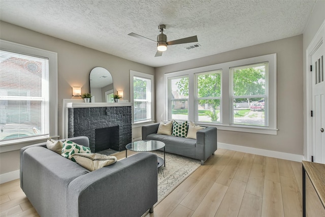 1522 Munger St, Houston, TX 77023 - living area featuring light wood finished floors, ceiling fan, baseboards, a fireplace, and a textured ceiling