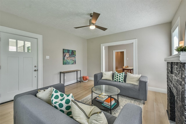 1522 Munger St, Houston, TX 77023 - living area with light wood-style floors, a ceiling fan, baseboards, and a textured ceiling