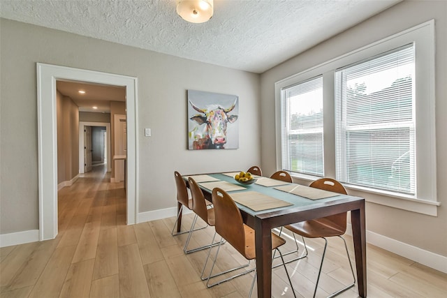 1522 Munger St, Houston, TX 77023 - dining space with baseboards, light wood-style floors, and a textured ceiling