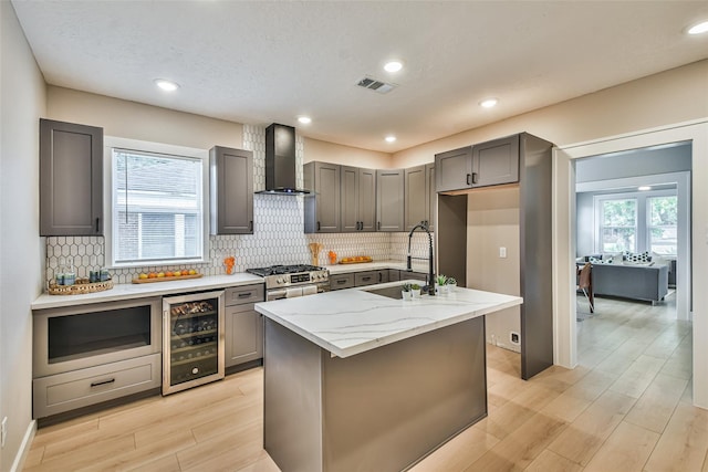 1522 Munger St, Houston, TX 77023 - kitchen featuring wine cooler, wall chimney exhaust hood, a sink, gray cabinetry, and light wood-style floors