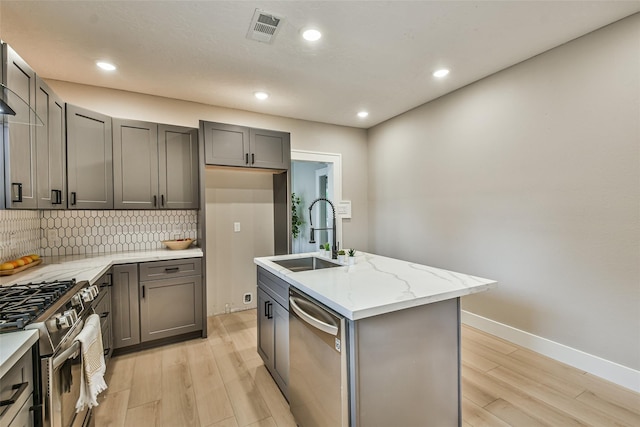 1522 Munger St, Houston, TX 77023 - kitchen featuring stainless steel appliances, a sink, light wood-type flooring, decorative backsplash, and gray cabinets