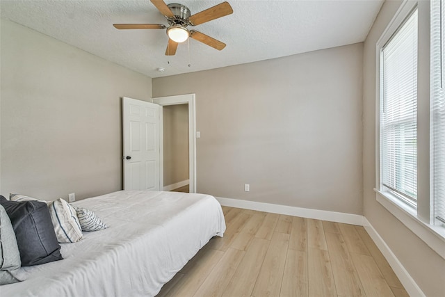 1522 Munger St, Houston, TX 77023 - bedroom with light wood-style flooring, baseboards, a ceiling fan, and a textured ceiling