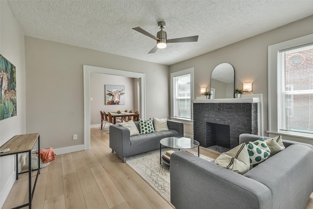 1522 Munger St, Houston, TX 77023 - living area with light wood finished floors, healthy amount of natural light, a fireplace, a ceiling fan, and a textured ceiling