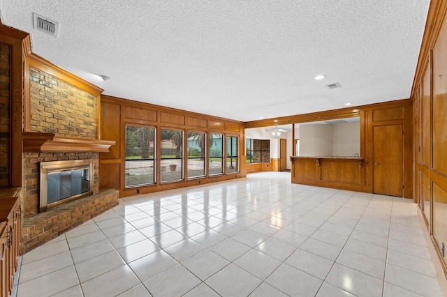 1211 Sycamore Ln, Houston, TX 77339 - unfurnished living room featuring a textured ceiling, wood walls, light tile patterned flooring, a fireplace, and crown molding