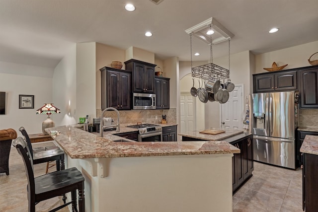 10910 Maddys Ct, Montgomery, TX 77316 - kitchen with appliances with stainless steel finishes, decorative backsplash, light stone countertops, a kitchen island, and a sink
