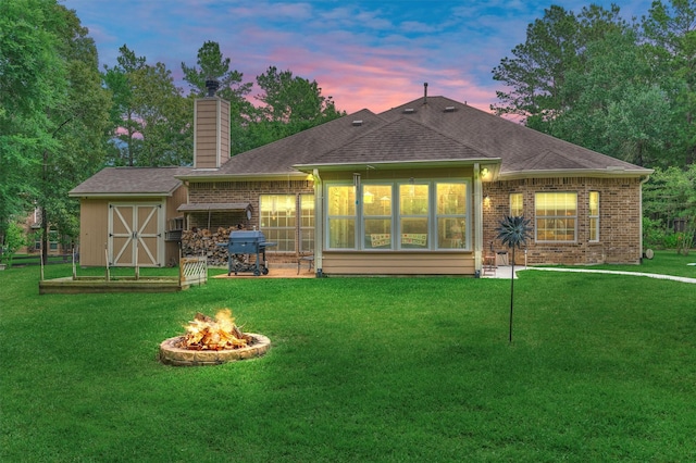 10910 Maddys Ct, Montgomery, TX 77316 - rear view of property featuring a chimney, a yard, a fire pit, brick siding, and a shingled roof
