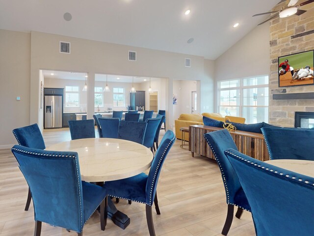 1306 Hidden Oaks Dr, Tomball, TX 77375 - dining room with a fireplace, light wood-style floors, ceiling fan, and high vaulted ceiling