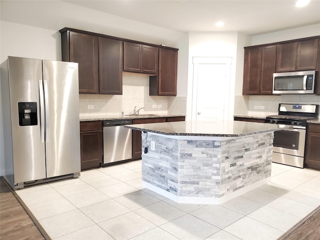 2726 Little Caney Way, Conroe, TX 77301 - kitchen featuring appliances with stainless steel finishes, dark brown cabinets, dark stone counters, a sink, and recessed lighting