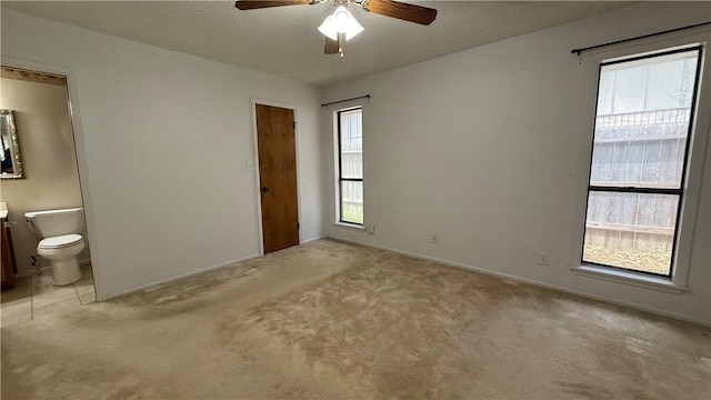 213 Yuma Dr, Victoria, TX 77904 - unfurnished bedroom featuring light colored carpet, baseboards, ensuite bath, a textured ceiling, and a ceiling fan